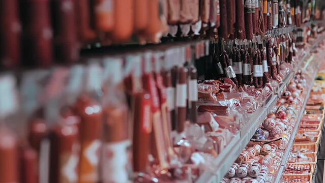 Smoked sausages in vacuum packaging are on shelves in store on sale. Row of meat products. Retail trade in shopping mall centre. Bacon. Food for people.