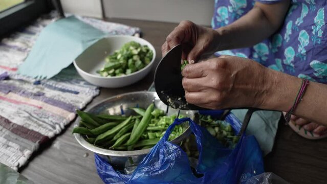 Weathered Hands Of Women Slicing Greens Beans Using Pahsul or Boti. Slow Motion