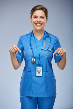 Smiling nurse woman pointing with fingers down. Isolated female portrait.