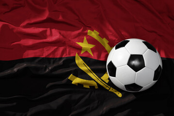Naklejka premium vintage football ball on the waveing national flag of angola background. 3D illustration