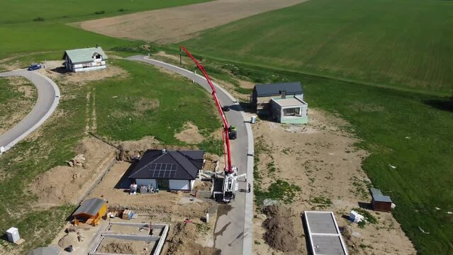 Drone rotating over concrete pump and crane over a new house building in small willage under mountains
