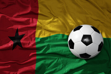 Naklejka premium vintage football ball on the waveing national flag of guinea bissau background. 3D illustration