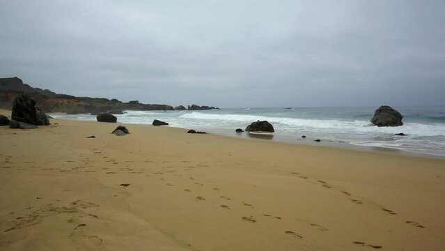Waves on sandy, cloudy Big Sur Garrapata Beach.