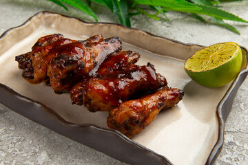 Fried chicken legs in a plate on a gray background.