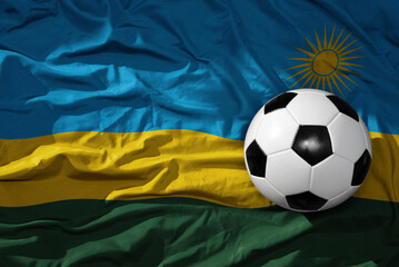 vintage football ball on the waveing national flag of rwanda background. 3D illustration