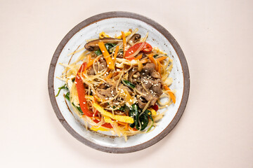 Japchae is Korean traditional dish, stir-fried Korean vermicelli noodles with vegetables and slices beeef, topping with sesame seeds.