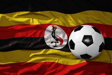 vintage football ball on the waveing national flag of uganda background. 3D illustration