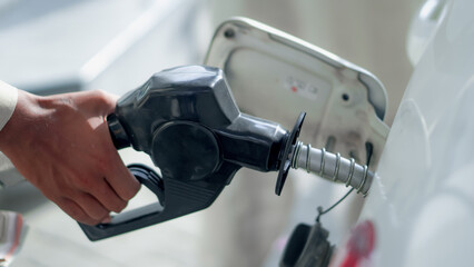 Hand holding fuel pump and refilling car at gas station