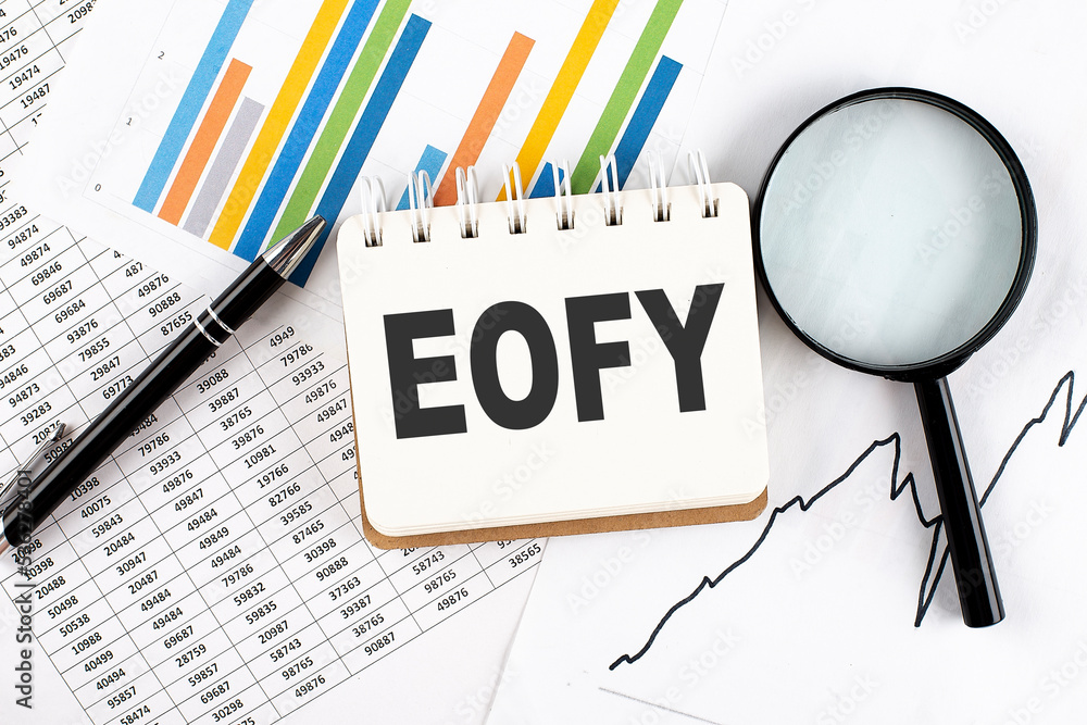 Poster eofy text on notebook on the graph background with pen and magnifier