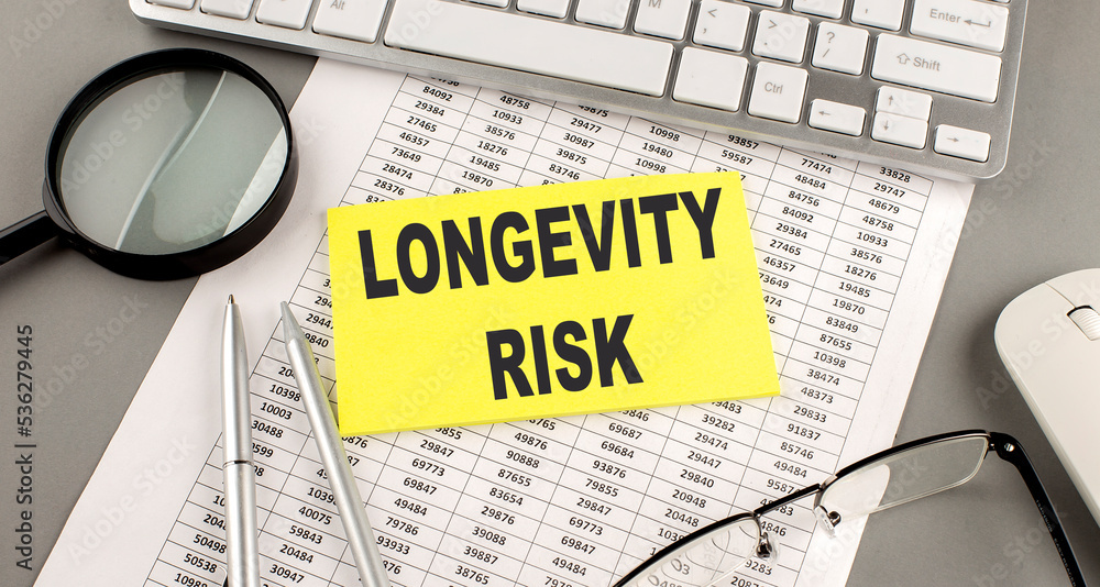Poster longevity risk text written on a sticky on chart with keyboard and magnifier