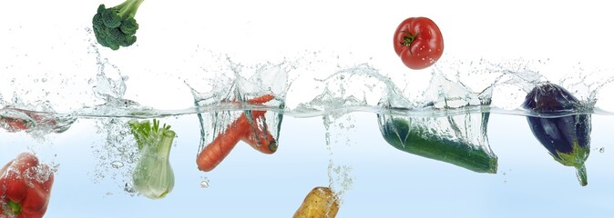 Many different vegetables splashing in water.