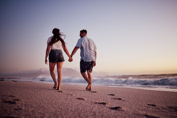 Love, holding hands and couple walking on the beach relax, bond and enjoy romantic quality time together in Israel. Peace, freedom and ocean air for man and woman on sea sand travel for wellness calm