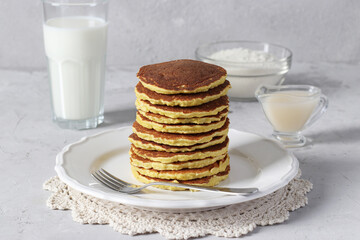Coconut flour pancakes on white plate on light gray background, vegan food