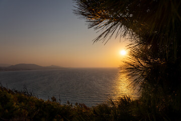 Panoramic view of Mediterranean Sea from sandy beach with rays of sun against backdrop of colorful sunset of Rhodes, Greece. Vacation, holiday concept. High quality photo