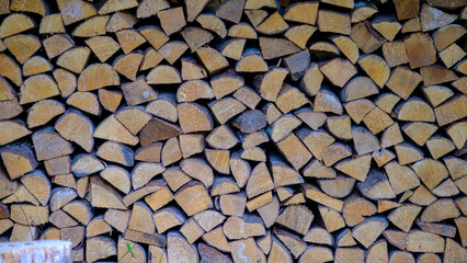 A wall of firewood, a background of dry chopped firewood stacked in several rows. Alternative fuel concept. Firewood for fireplace or stove heating.