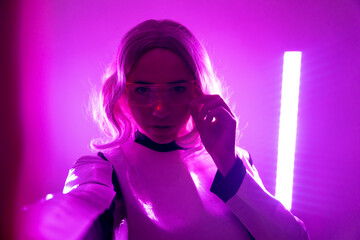 Fototapeta na wymiar Woman in futuristic suit and glasses with pink led lights, virtual concept, metaverse, selfie with camera