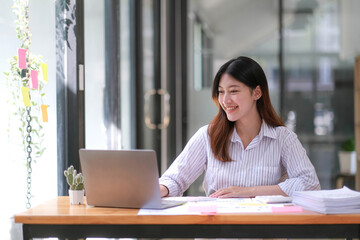 Young Asian businesswoman is happy to work at the modern office using a tablet.