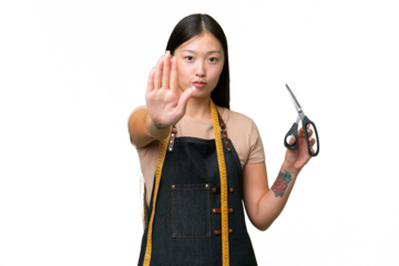 Young Asian seamstress woman over isolated background making stop gesture