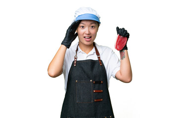 Young caucasian woman wearing an apron and serving fresh cut meat over isolated background with surprise expression
