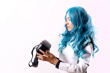 Woman with blue hair and wearing virtual reality glasses, futuristic concept, looking at the glasses