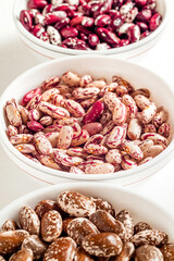Organic beans in white ceramic bowls. Scarlet runner, pinto, anasazi beans. Rich in protein.