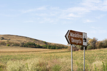 Road sign to the monastery Dinogetia in Jiji La Commune, Garvan Village, Romania. Horizontal. The inscription on the sign: Dinogetia Monastery
