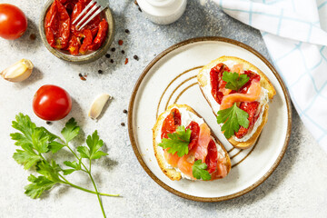 Open sandwiches or bruschetta with salted salmon, cheese and sun dried tomato on a stone table. Healthy food, seafood. View from above.