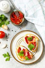 Open sandwiches or bruschetta with salted salmon, cheese and sun dried tomato on a stone table. Healthy food, seafood. View from above.