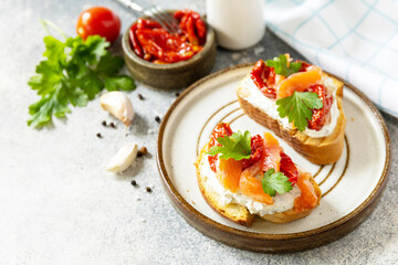Open sandwiches or bruschetta with salted salmon, cheese and sun dried tomato on a stone table. Healthy food, seafood. Copy space.