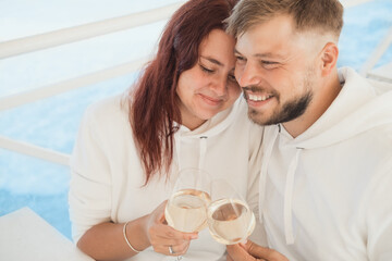 A man and a woman are sitting in a cafe and drinking white wine. 