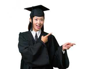 Young university graduate Asian woman over isolated background surprised and pointing side