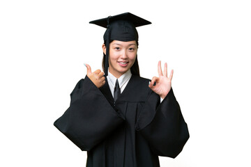 Young university graduate Asian woman over isolated background showing ok sign and thumb up gesture