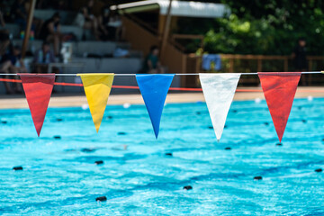 Multi-colored triangle swim marker flags hanging above a swimming pool