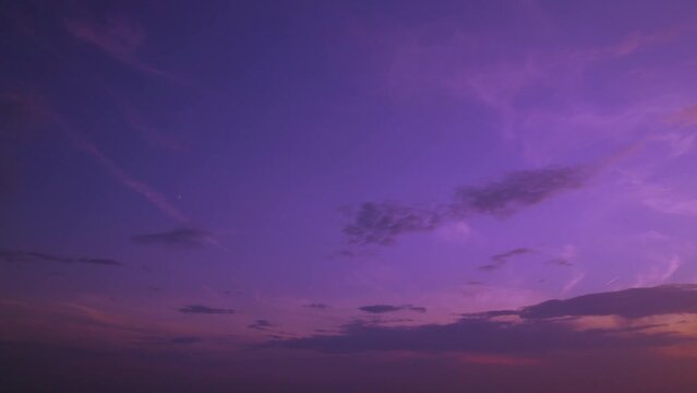 A colored evening sunset sky with a brilliant glow. The sun shines through the clouds and creates a purple gradient. At sunrise, a colorful heaven with solar rays streaming through the cloudscape.