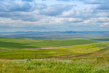 Bald Mountain in the Buryat Republic of Russia. Green hills against a blue sky with clouds.
