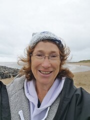 Senior woman takes a selfie for social media after a cold water swim in the sea. Open or cold water swimming in the sea is known to have benefits for physical and mental health.