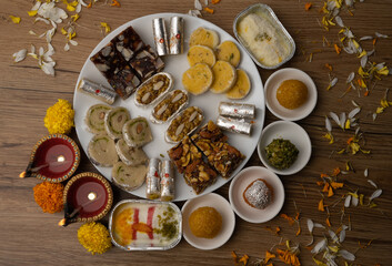 Mix indian sweets like kaju roll dryfruits barfi mango peda served in a plate