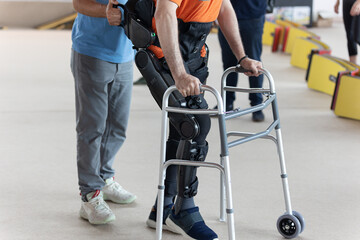 Boy with Mobility Problems in Lower Limbs in Upright Posture Walking Thanks to a Mechanical...