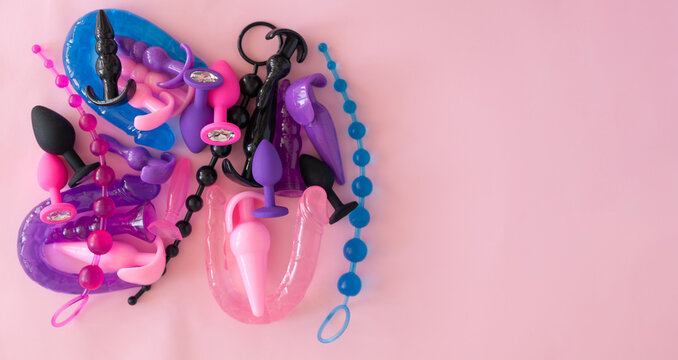 Different multicolored silicone sex toys on a pink background. Erotic toy for fun. Diffrent anal butt plugs. Banner with space for text