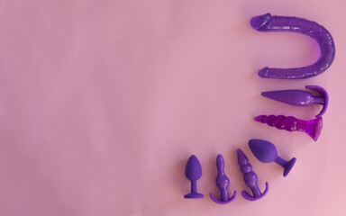 purple silicone sex toys on a pink background. Erotic toy for fun. Diffrent anal butt plugs....