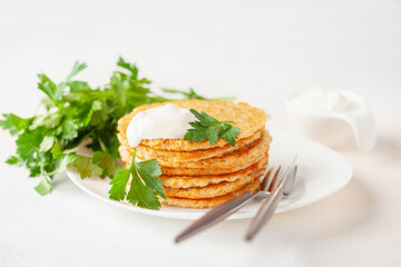 Potatoes pancakes latkes, flapjacks, hash brown or potato vada with parsley and sour cream  on table.