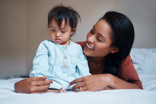 Love, Mother And Down Syndrome Baby In Bedroom Together To Relax And Bond In Puerto Rico House. Care, Love And Support Of Mom Embracing Child With Mental Disability On Bed In Happy Family Home.