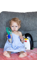 a child with snot holds a mask from a nebulizer in his hands.