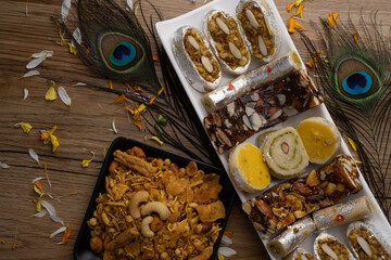 Mix indian sweets like kaju roll dryfruits barfi mango peda served in a plate