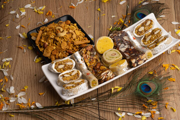 Mix indian sweets like kaju roll dryfruits barfi mango peda served in a plate