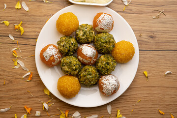 plate full of assorted laddoos like motichur laddoo, bundi ladu and pistchio laddu with farsan or namkin
