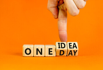 One day and idea symbol. Concept words One day and One idea on wooden cubes. Businessman hand. Beautiful orange table orange background. Business One day and idea concept. Copy space.