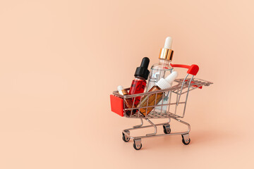 Online shopping minimalistic concept. Small cart with cosmetic bottles. Essential oil, serum and peeling gel in glass droppers. Mixture of beauty products. Black Friday Sales