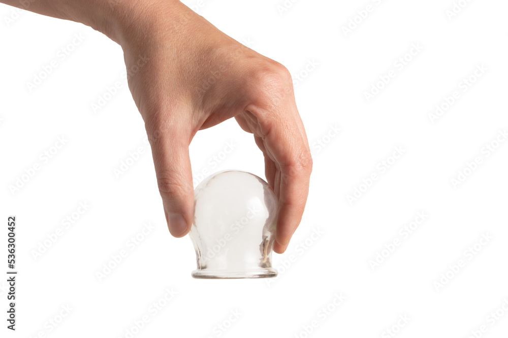 Wall mural a hand holding a glass cup for cupping therapy, isolated on white, close-up.