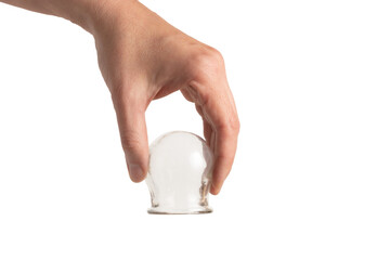 A hand holding a glass cup for cupping therapy, isolated on white, close-up.